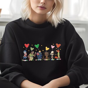A woman wearing a black sweater with a colorful graphic of cartoon characters and animals printed on it.
