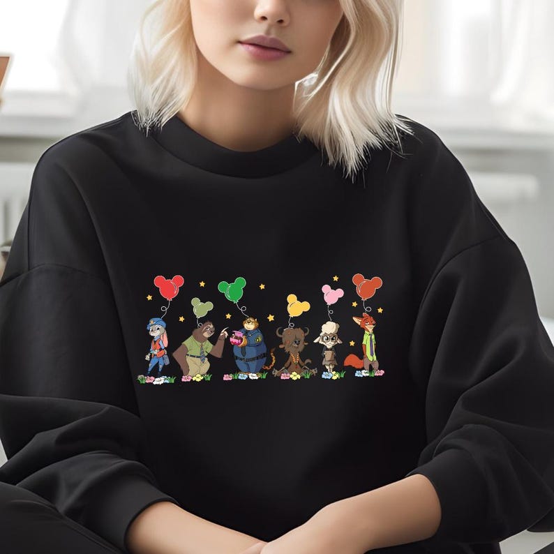 A woman wearing a black sweater with a colorful graphic of cartoon characters and animals printed on it.