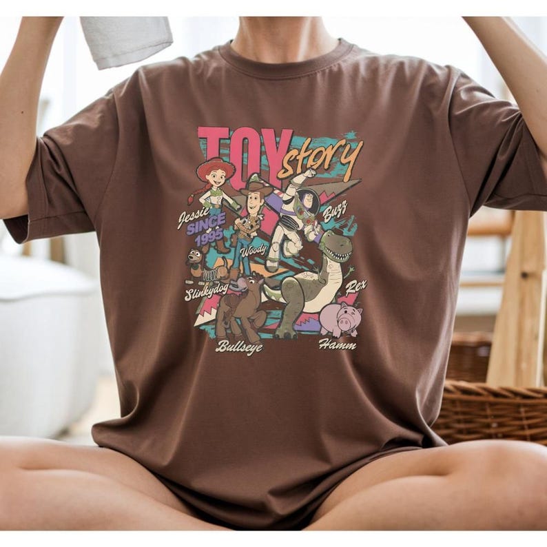 a person wearing a brown t-shirt with a colorful graphic design depicting characters from the Toy Story movie.