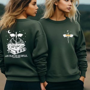 Two women wearing green sweatshirts with a dragon design and text on the back.