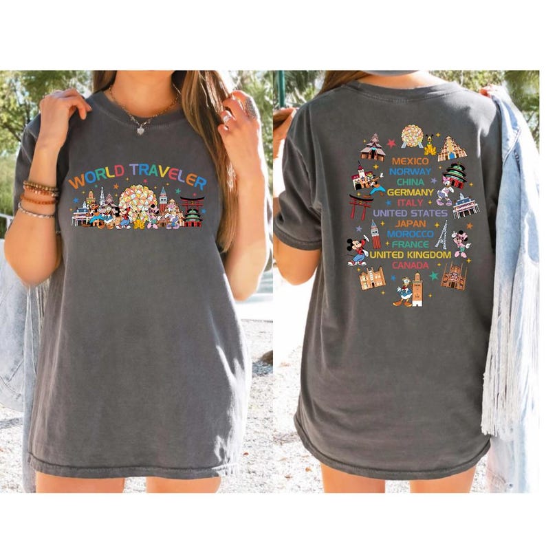 a woman wearing a gray t-shirt with a colorful graphic design depicting various landmarks and icons from different countries, including Mexico, Norway, Germany, Japan, the United States, and Morocco.