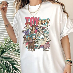 A person wearing a white t-shirt with a colorful graphic of characters from the Toy Story movie.