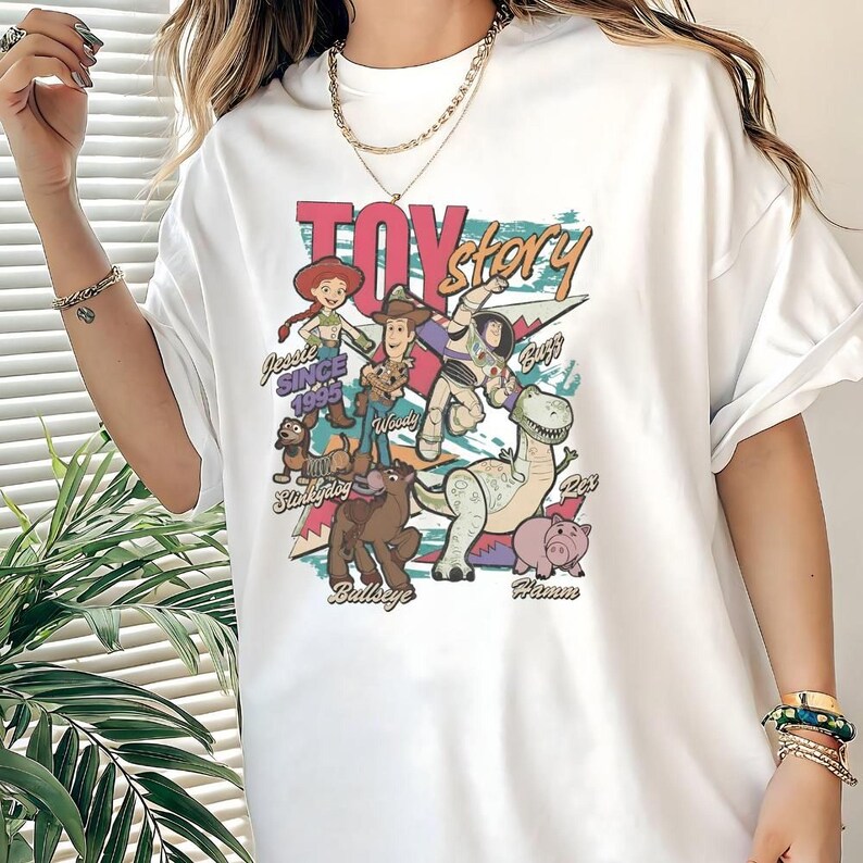 A person wearing a white t-shirt with a colorful graphic of characters from the Toy Story movie.
