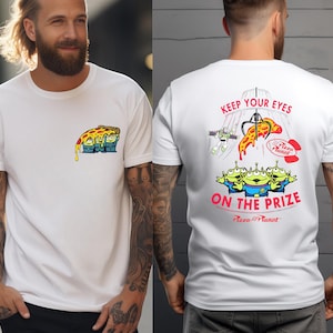 May include: White t-shirt featuring a colorful cartoon pizza slice with three green aliens. The back of the shirt has the text "KEEP YOUR EYES ON THE PRIZE" with a claw machine and more aliens.