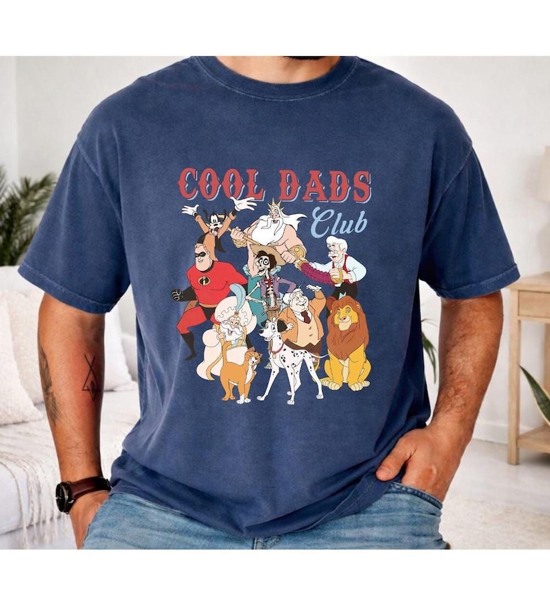 A man wearing a blue t-shirt with a graphic design featuring various cartoon characters, including a lion, a dog, and other animals.