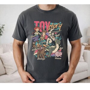 a man wearing a black t-shirt with a colorful graphic design depicting characters from the Toy Story movie.