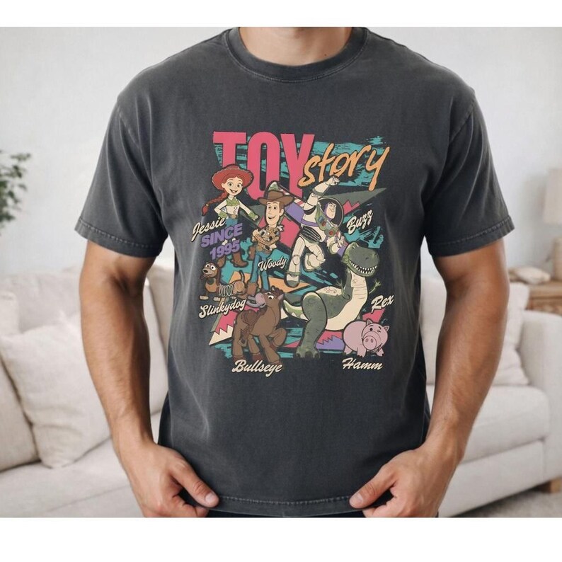 a man wearing a black t-shirt with a colorful graphic design depicting characters from the Toy Story movie.