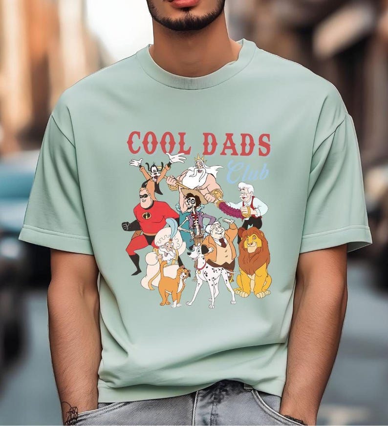 A man wearing a light green t-shirt with a graphic design featuring various cartoon characters.