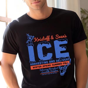 以下が含まれることがあります： クリストフとスヴェンのアイスハーベスティング＆デリバリーサービスの青いオレンジのグラフィックが描かれた黒いTシャツ。グラフィックには、オラフとスヴェンのカートゥーン画像が含まれています。
