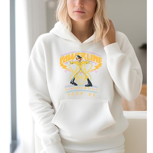 May include: White hoodie with a yellow and black graphic of a cartoon character holding two lightning bolts. The graphic says "Powerline S.O.U.T. Tour '95".