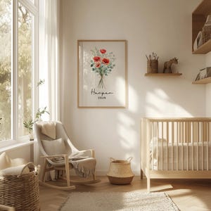 Puede incluir: Un cuadro enmarcado con un ramo de amapolas rojas y follaje verde, con los nombres "Harper" y "Evelyn" debajo. El cuadro cuelga en una habitaci&oacute;n infantil, junto a una cuna de madera, una mecedora y cestas de mimbre.