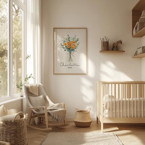 May include: A framed floral print with orange and green flowers, the name "Charlotte" and "Marie" in script. The print hangs above a rocking chair and a crib in a nursery. A woven basket and rug are in the foreground.