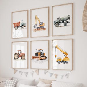 Op de afbeelding: Zes ingelijste aquarelprints van bouwmachines. De prints tonen een dumper, graafmachine, betonmixer, tractor, bulldozer en kraan. De voertuigen zijn in tinten oranje, geel en grijs, tegen een witte achtergrond.