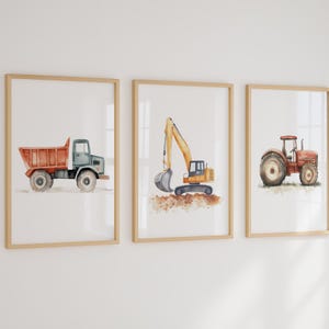 Puede incluir: Conjunto de tres láminas enmarcadas en acuarela con vehículos de construcción. Incluye un camión volquete rojo, una excavadora amarilla y un tractor rojo. Cada lámina está en un marco de madera.