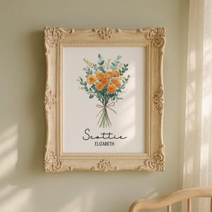 May include: A framed floral print featuring a watercolor bouquet of orange flowers and green foliage tied with a brown ribbon. The print is in a cream-colored ornate frame. The name "Scottie" and "Elizabeth" are written below the bouquet.