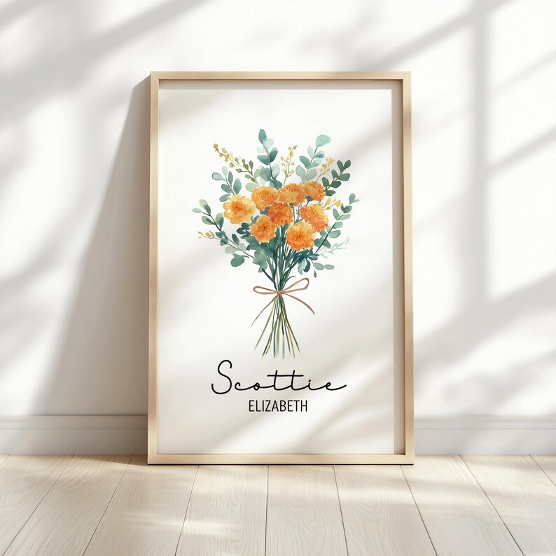 May include: A framed watercolor print featuring a bouquet of orange flowers and green foliage tied with a brown ribbon. The names "Scottie" and "Elizabeth" are written in script below the flowers. The frame is a light wood color.