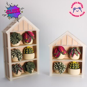 May include: Two light-colored, house-shaped shelves displaying miniature potted plants. The taller shelf has three levels, the shorter has two. The plants feature various green, pink, and yellow textures. A purple 'CLICK' burst and a 'MARIE'S BUTTON AUTHORIZED SELLER' logo are visible.