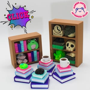 Könnte beinhalten: Miniatur-braune Bücherregale mit Büchern, einem Frosch, einem Totenkopf und einer Uhr. Mehrere Stapel Bücher mit einer Tasse Kaffee und einer schlafenden Katze vor den Regalen. Das Wort "CLICK" befindet sich in einer Sprechblase.