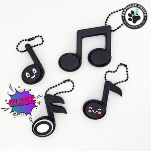 May include: Four black musical note keychains with different designs. One has a smiley face, one has a winking face, one has a simple design, and one has a musical note design. The keychains are on a white background.