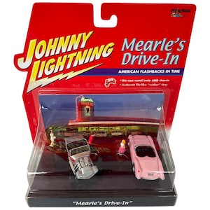 May include: A Johnny Lightning die-cast model of Mearle's Drive-In, featuring a pink classic car and a silver hot rod. The packaging is red with the text "Johnny Lightning" and "Mearle's Drive-In". The model includes a diorama of the drive-in.