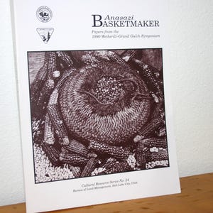 May include: A black and white book cover titled "Anasazi Basketmaker" with an illustration of a woven basket surrounded by corn. The book is from the 1990 Wetherill-Grand Gulch Symposium. The cover also includes the text "Cultural Resource Series No. 24".