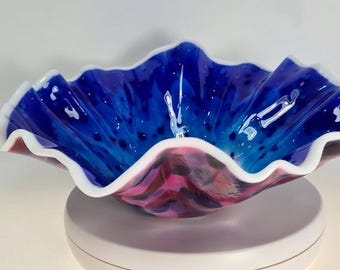 Een centrale kom van gesmolten glas in opvallende blauwe, paarse en roze tinten.