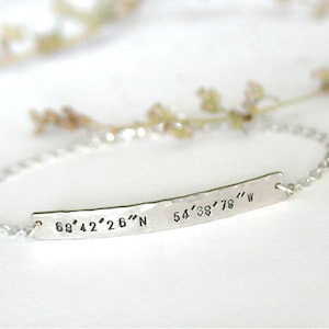 Op de afbeelding: Zilveren armband met een gegraveerde, gehammerde staafbedel met de coördinaten "68° 42' 26" N 54° 38' 78" W".