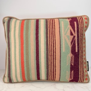 May include: A rectangular throw pillow featuring a woven pattern of vertical stripes in shades of sage green, deep burgundy, peach, and bright orange. The pillow has a tan piped edge and a small black tag on the right side with the text PENDLETON.