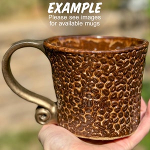 May include: A brown ceramic coffee mug with a gold handle. The mug is decorated with a pattern of coffee beans.