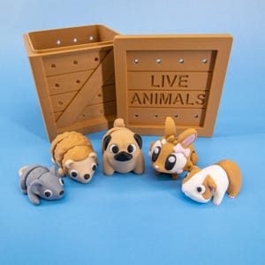 以下が含まれることがあります： ハリネズミ、パグ、鹿、モルモット、ネズミなど、小さな動物の彫刻フィギュアのコレクションが、木製の箱の前に配置されています。 箱には「LIVE ANIMALS」と書かれており、明るい茶色です。 背景は無地の青色です。