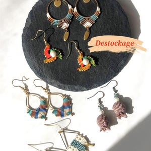 Peut inclure: Une collection de boucles d'oreilles faites à la main de différents styles, dont des créoles, des gouttes et des spirales. Les boucles d'oreilles présentent du macramé et des perles dans des couleurs comme le marron, le bleu, le blanc et le rouge.