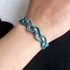 May include: A blue and green braided bracelet with silver beads.