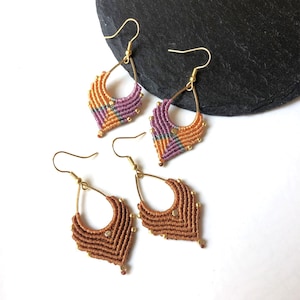 May include: Four pairs of handmade macrame earrings. The earrings feature a teardrop shape with a woven design in shades of brown, orange, purple, and gold. The earrings have gold-coloured ear wires and small gold beads.
