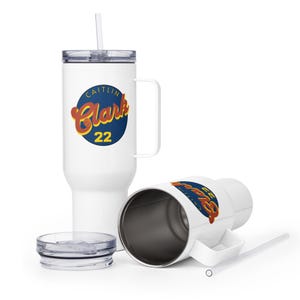 May include: White insulated travel mug with a handle, lid, and straw. The mug displays a blue circle with the name "Caitlin Clark" in orange script and the number "22" in yellow.