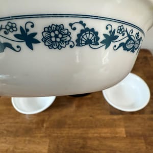 Puede incluir: Cuenco de cerámica blanco con un diseño floral turquesa alrededor del borde. Se ven dos cuencos blancos pequeños debajo. El cuenco tiene una estética clásica y vintage, adecuado para servir o exhibir.