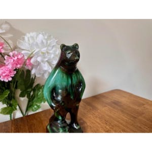 Könnte beinhalten: Keramik-Bärenfigur mit glänzendem Finish. Der Bär hat einen dunkelbraunen Kopf und Beine mit einem leuchtend grünen und braunen Körper. Die Figur steht aufrecht und hat ein detailliertes, strukturiertes Aussehen. Der Bär ist ein dekorativer Artikel.