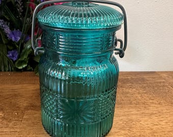 Tarro de vidrio azul verdoso vintage de Avon con asa de alambre texturizado, contenedor de almacenamiento retro