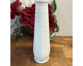 May include: A white, diamond-patterned vase with a cylindrical shape. The vase is made of ceramic or glass and has a flared top. Red and white flowers are in the background. The vase is approximately 10 inches tall.