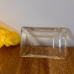 Puede incluir: Un cenicero rectangular de vidrio transparente con bordes ligeramente redondeados.
