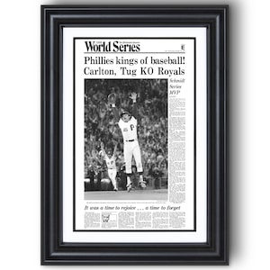 May include: Framed black and white print of a newspaper article. The headline reads "Phillies kings of baseball!" with a photo of a baseball player celebrating. The text "World Series" is at the top.