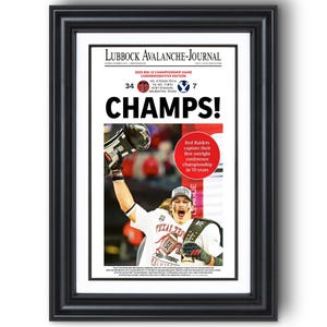 May include: Framed newspaper front page with the headline "CHAMPS!" and a photo of a football player celebrating. The text reads "2025 Big 12 Championship Game Commemorative Edition." The score is 34-7. The article is about the Red Raiders winning their first outright conference championship in 70 years.