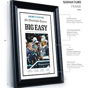 May include: A black framed print of a newspaper article from The Philadelphia Inquirer with the headline "BIG EASY" and a photo of a football player holding a trophy. The frame is 23 inches tall and 17 inches wide.