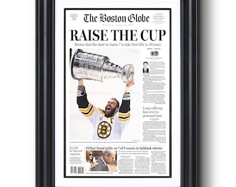 Puede incluir: Una página de periódico en blanco y negro con el titular "Raise the Cup" y una foto de un jugador de hockey sosteniendo la Copa Stanley. El texto "Bruins shut the door in Game 7 to take first title in 39 years" está debajo del titular.