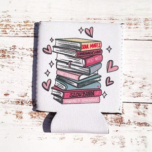 May include: White can cooler with a stack of books with titles like "Soul Mates", "Forbidden Love", "Fated Mates", "Love Triangle", and "Slow Burn" with pink hearts around the books.