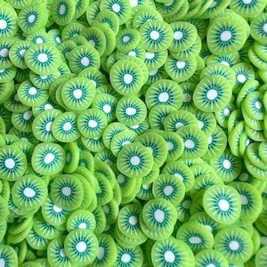 Puede incluir: Primer plano de numerosas rodajas de kiwi verdes. Cada rodaja tiene un centro blanco con líneas blancas radiantes y un anillo exterior verde oscuro. Las rodajas están dispersas, creando un patrón texturizado y vibrante.