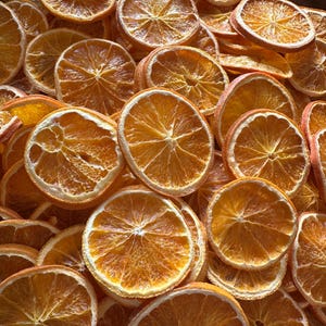 May include: A collection of dried orange slices, presented in a close-up view. The slices exhibit a rich orange hue, with a semi-transparent quality. The texture of the dried fruit is evident, showcasing the segments and the outer peel. The lighting accentuates the details of the fruit.