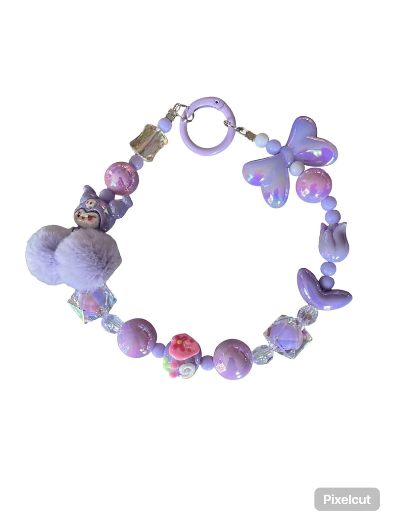 Pu&ograve; includere: Un braccialetto stravagante nei toni del lavanda, lilla e bianco iridescente. Il braccialetto presenta una variet&agrave; di perline, tra cui elementi rotondi, quadrati e a forma di fiore. Un soffice pompon lavanda e un ciondolo a forma di personaggio dei cartoni animati aggiungono un tocco giocoso.