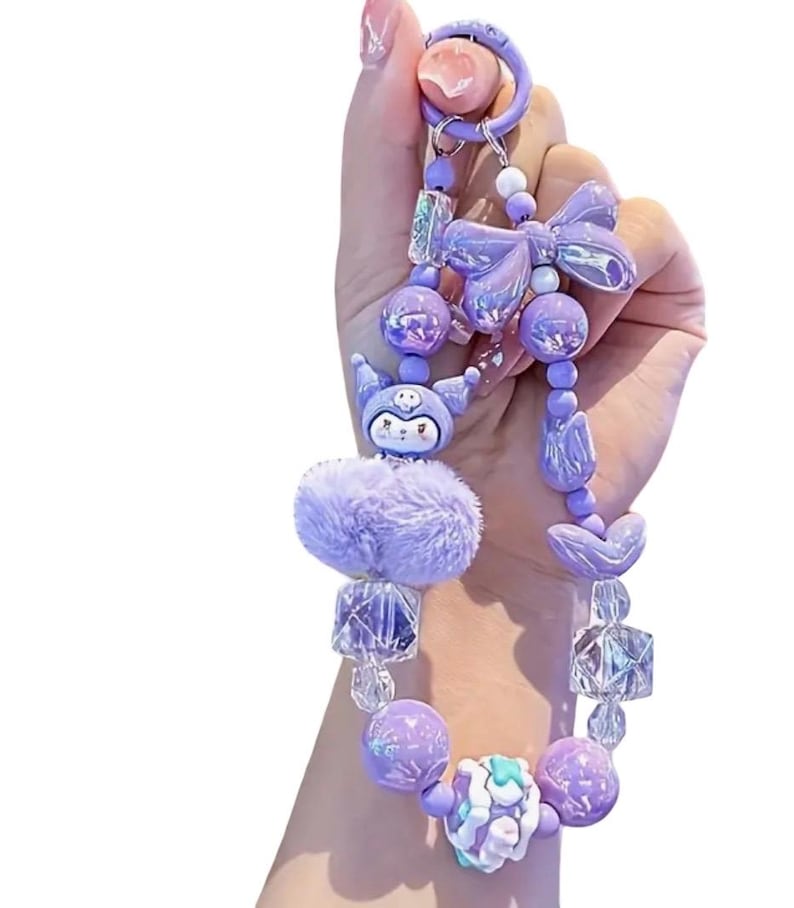 Pu&ograve; includere: Un portachiavi con perline viola con una variet&agrave; di elementi decorativi. Il portachiavi presenta un soffice pompon, un personaggio dei cartoni animati, un fiocco e varie perline nelle tonalit&agrave; del viola e del trasparente. Il portachiavi &egrave; tenuto da un anello viola.