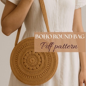 Op de afbeelding: Een ronde bruine gehaakte tas met een bloemenpatroon. De tas wordt vastgehouden door een persoon die een witte jurk draagt. De tekst "BOHO ROUND BAG Pdf pattern" is over de afbeelding gelegd.
