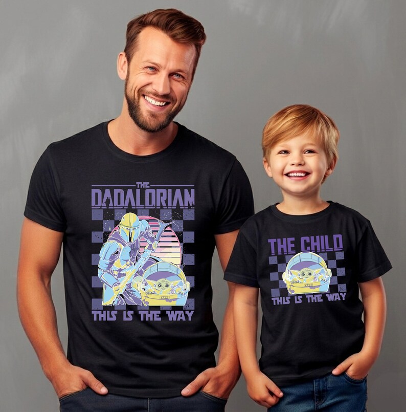 A man and a young boy wearing matching black t-shirts with the text "The Dadorian This is the Way" printed on them.